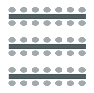 Room set up with rows of tables and chairs on either side of each row.