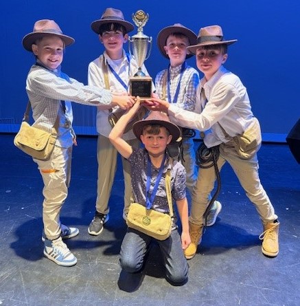 Five boys in fedora's and satchels holding up the Championship Trophy