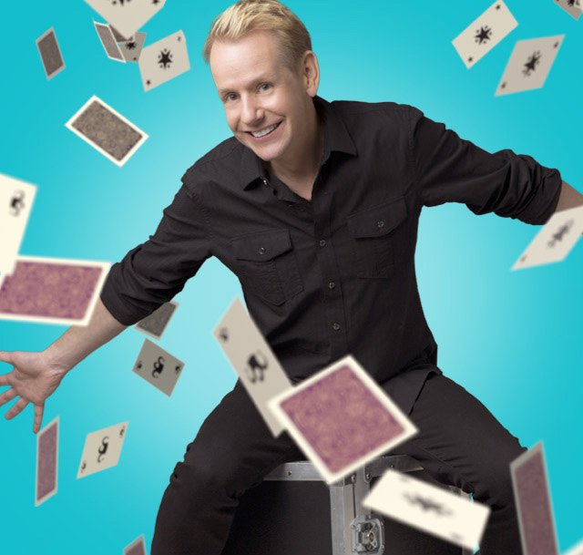 man in a black outfit with playing cards flying around him