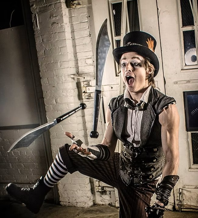 man in black clothes and a top hat juggling knives